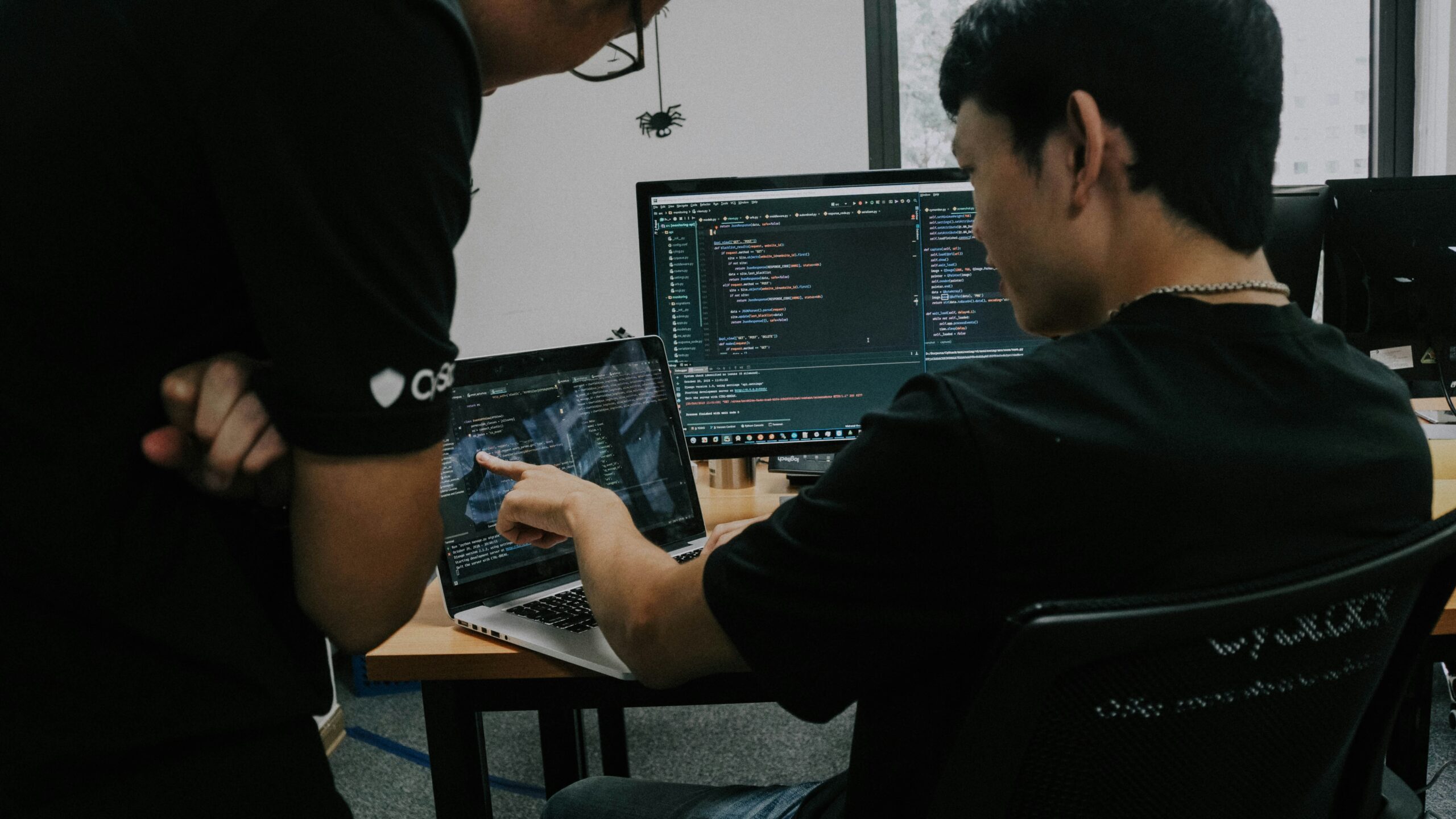 Two developers reviewing code on a laptop and monitor