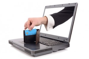 Theft over the internet concept with a hand poping out of the screen to steal a credit card, isolated on a white background