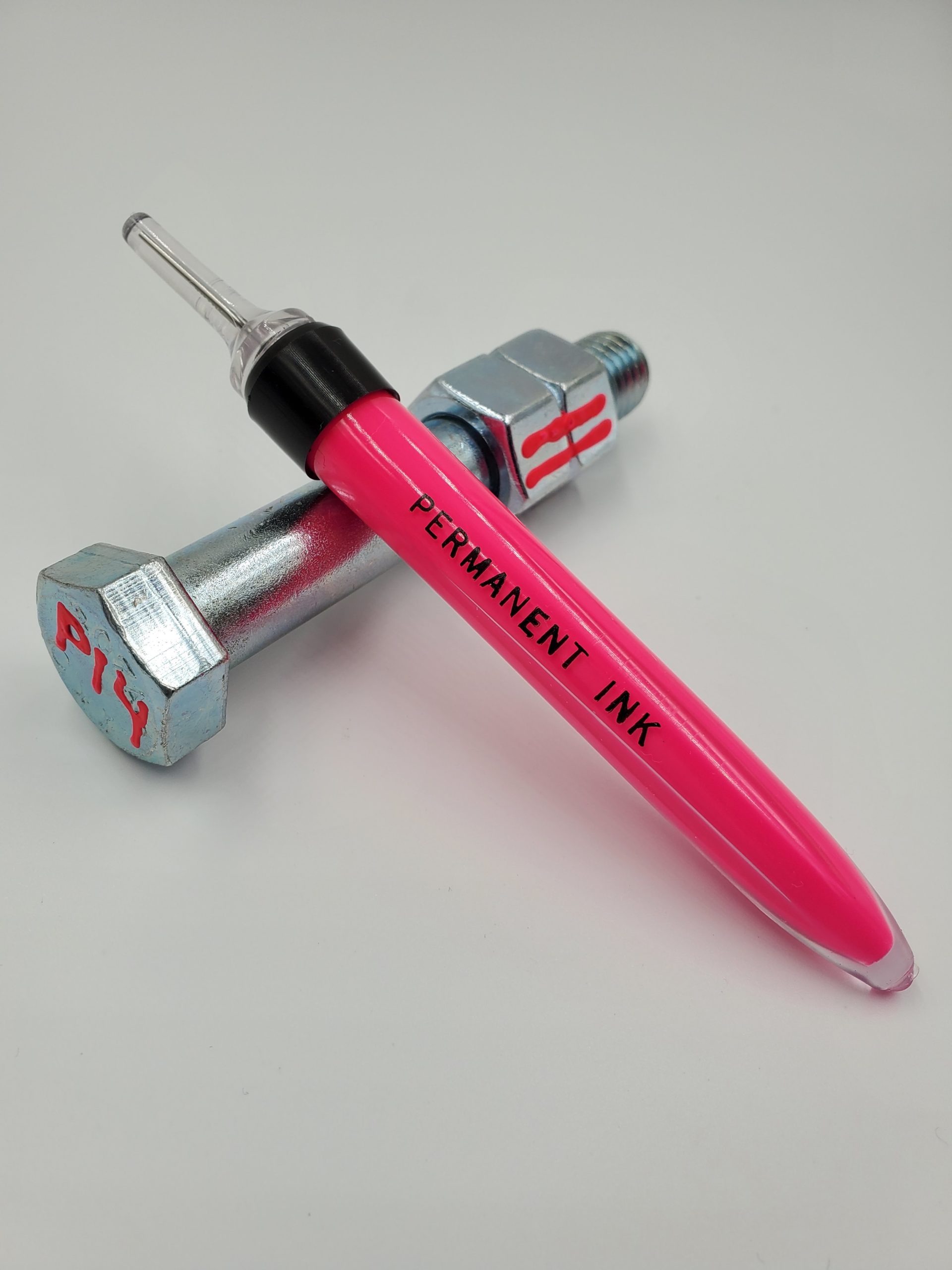Metron Marker filled with Hot Pink Ink laying on bolt with the letters P14 written in Hot Pink on one end and two strips of the ink drawn across double bolts showcasing flexibility, color and ink being used as tamper resistant seal, torque seal, torque stripe, and vibration aid.